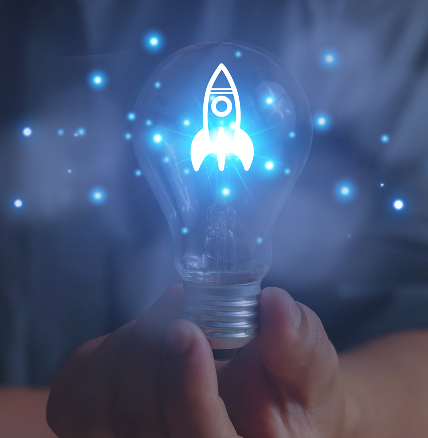 Eine Person hält eine Glühbirne mit einer leuchtenden Rakete in der Hand.
